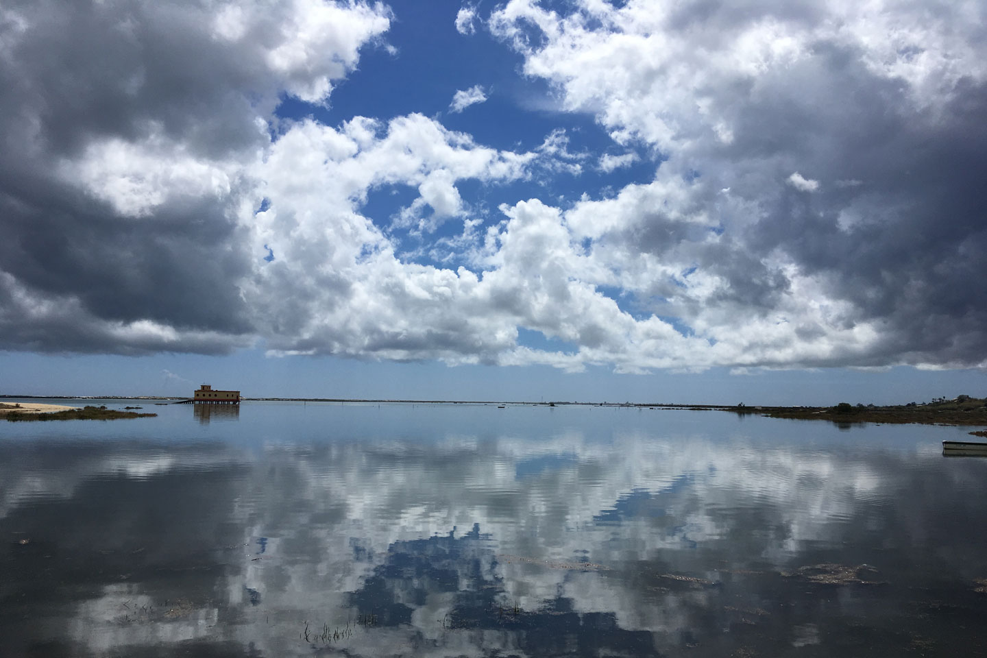 A photo of the abandoned lifeboat station in Fuseta, with clouds reflected onto the sea