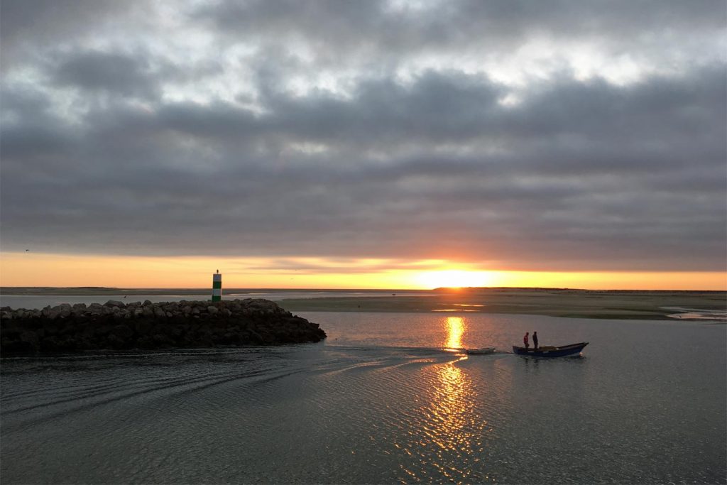 A photo of a boat leaving the quay at Fuseta at dawn