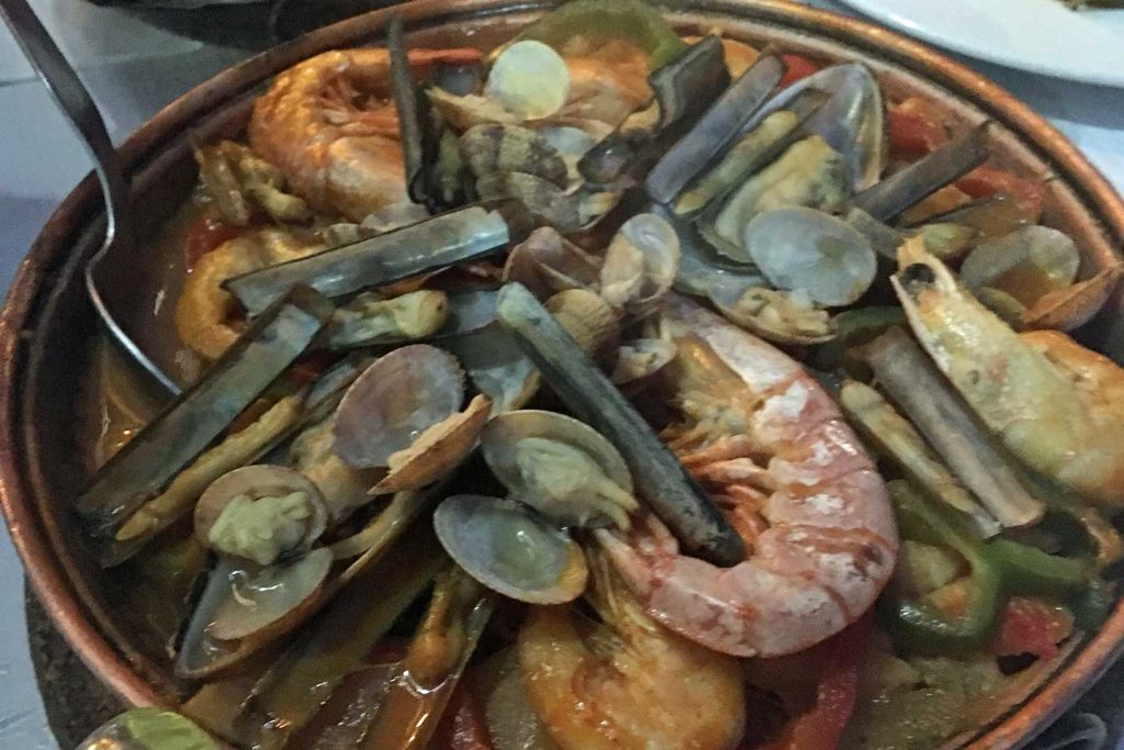 A photo of a large Cataplana dish, filled with prawns, clams, razorfish etc