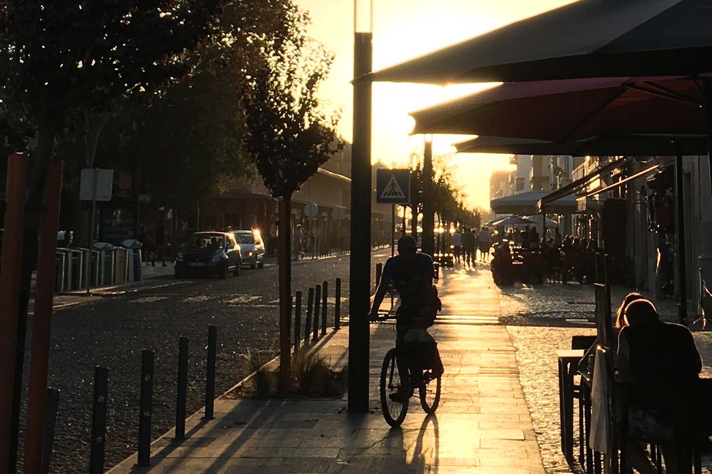 A man on a bike cycling down the Avenida da 5 Outubro in Olhao at twilight