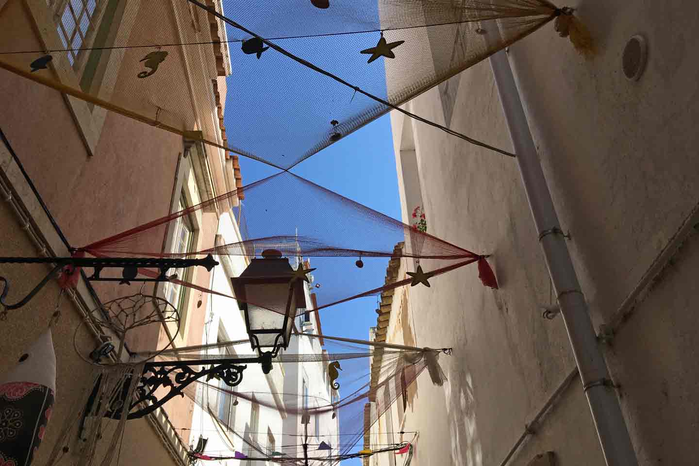 A photo of street decorations across an alleyway in Olhao