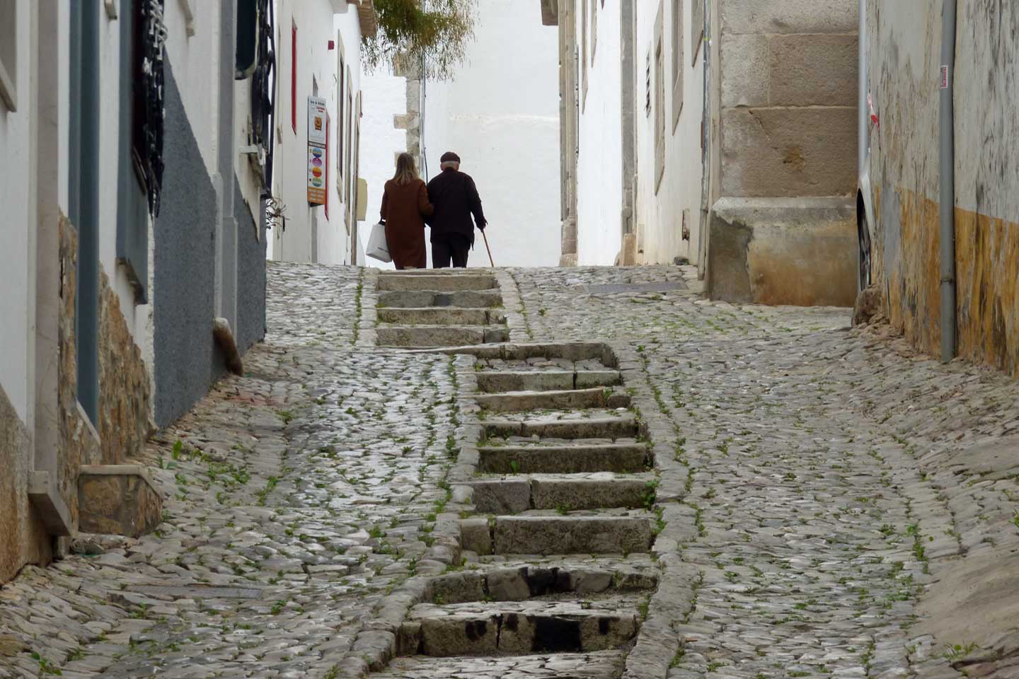 A photo of an old couple climbing steps in Tavira